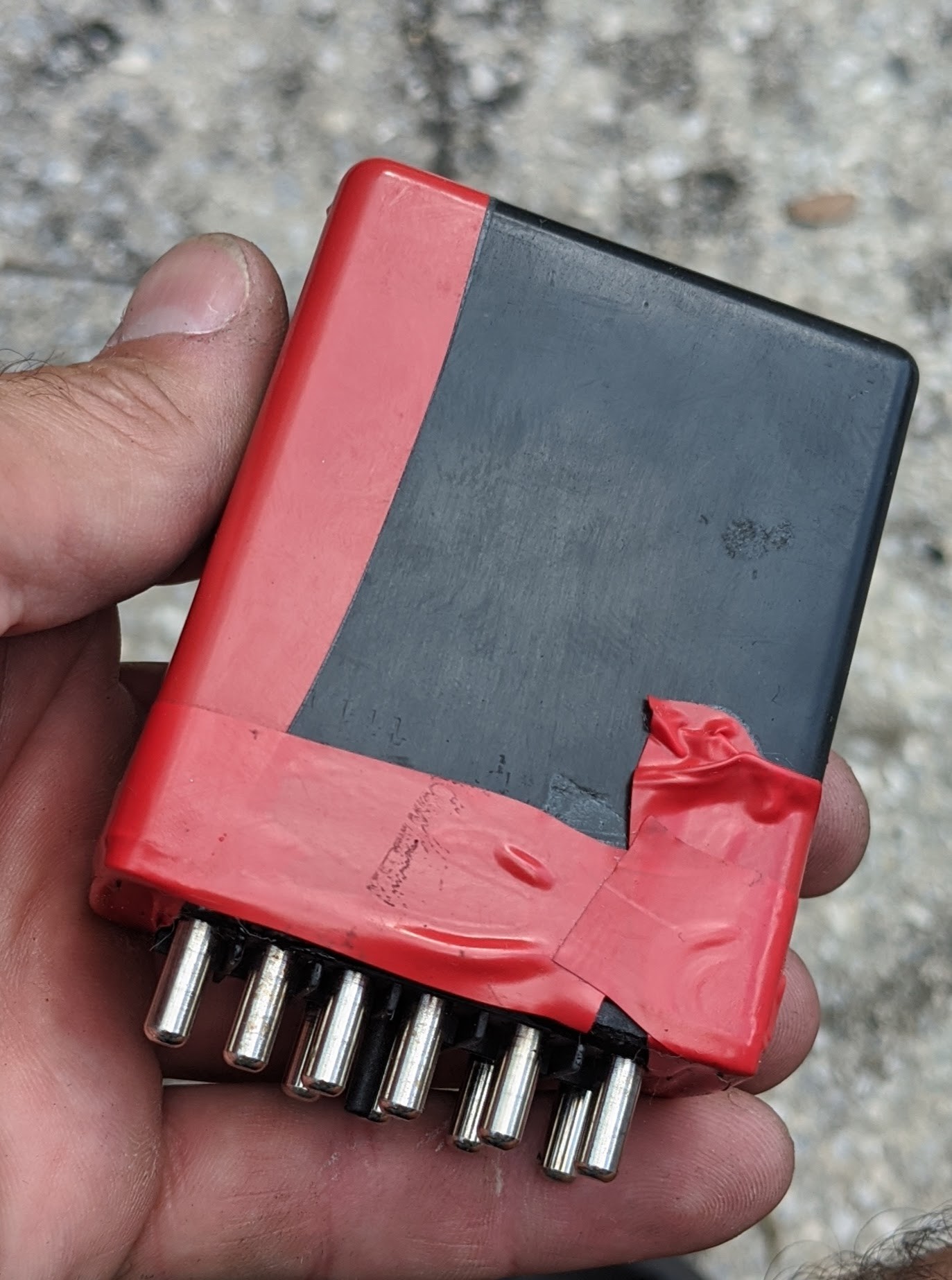 Close-up of the removed fuel pump relay and idle speed relay from a Mercedes 560 SL, showing the relays located behind the glove box access panel.