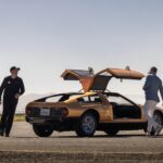 Mercedes-Benz C111 in Tawny Metallic paint driving on an airstrip, showcasing its iconic wedge shape and futuristic design.