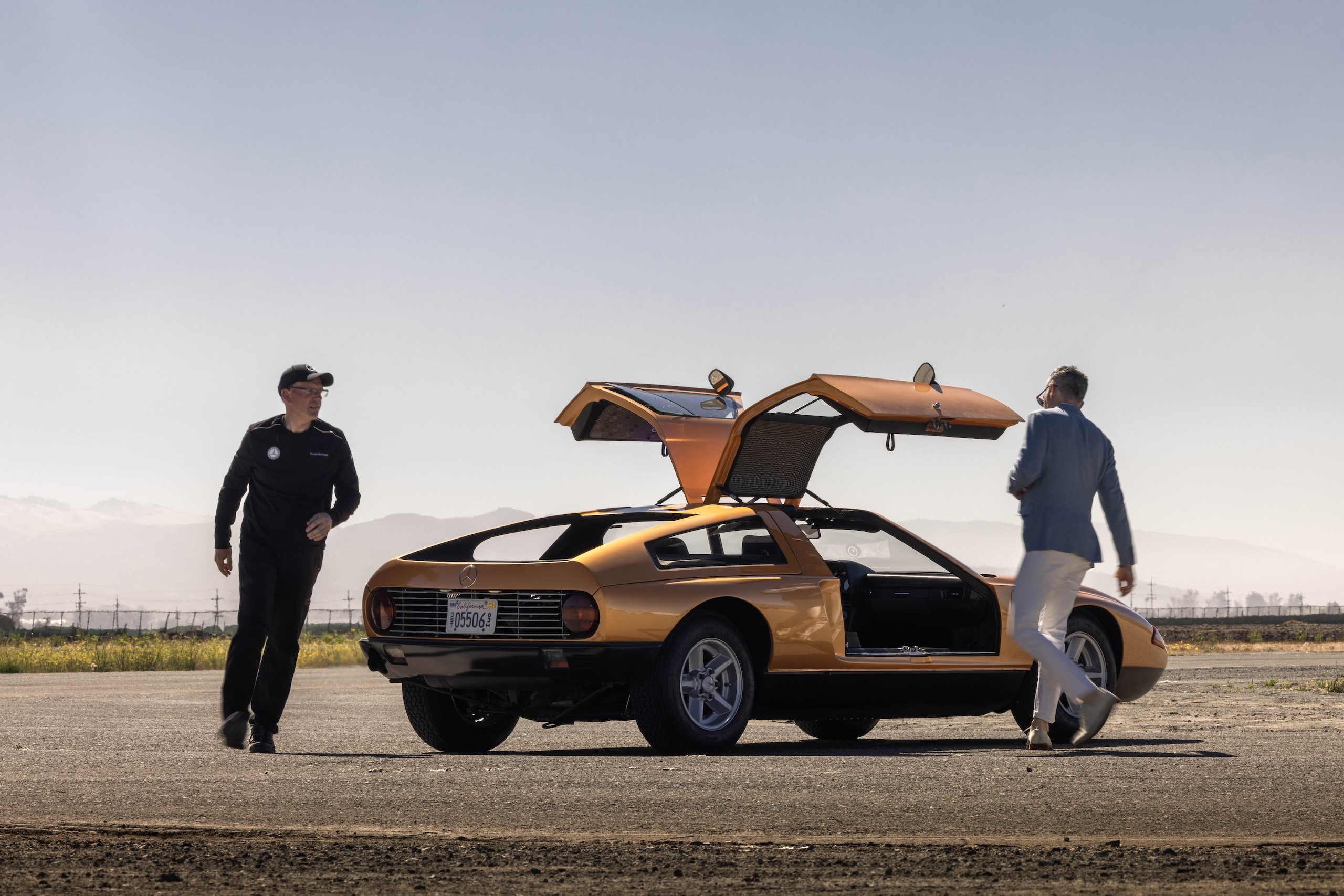 Mercedes-Benz C111 in Tawny Metallic paint driving on an airstrip, showcasing its iconic wedge shape and futuristic design.