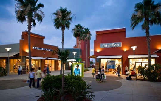 Exterior view of Rio Grande Valley Premium Outlets with blue sky and palm trees