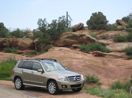 Side view of a silver Mercedes-Benz GLK 350 on a paved road showcasing its boxy silhouette.